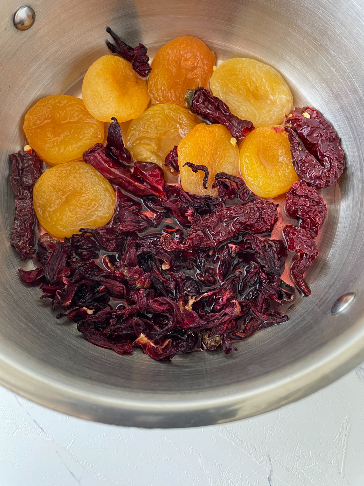 apricot, hibiscus flower and dried chilies in a pan 