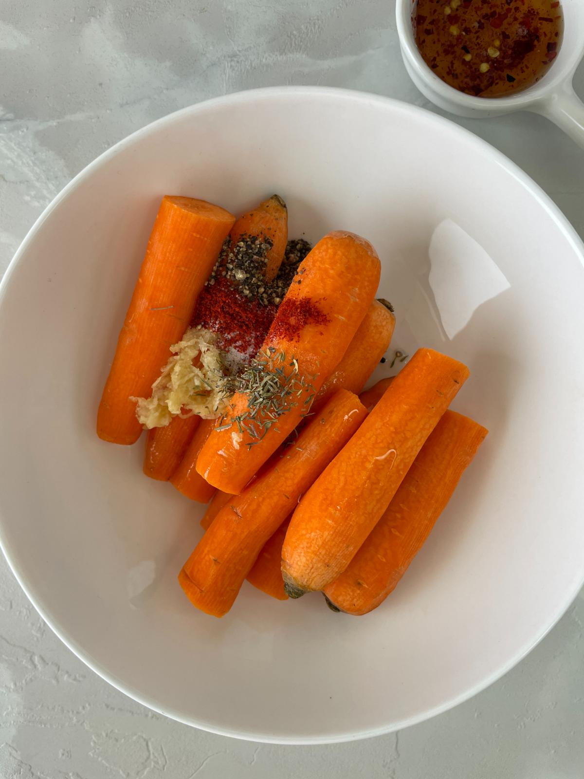adding spices and seasonings to the carrots