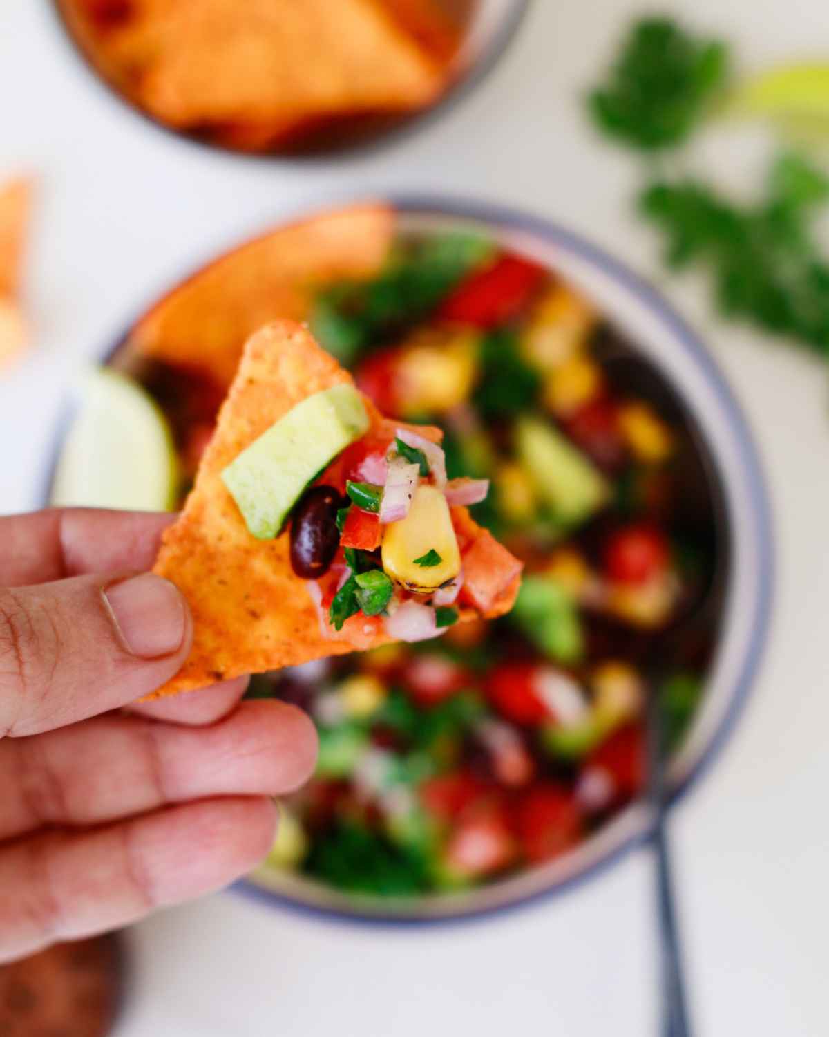 A piece of nacho in hand is holding Mexican Caviar