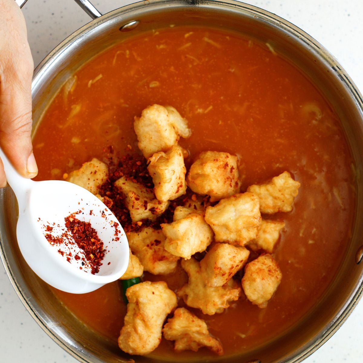 Add fried chicken pieces and add some red chili flakes 