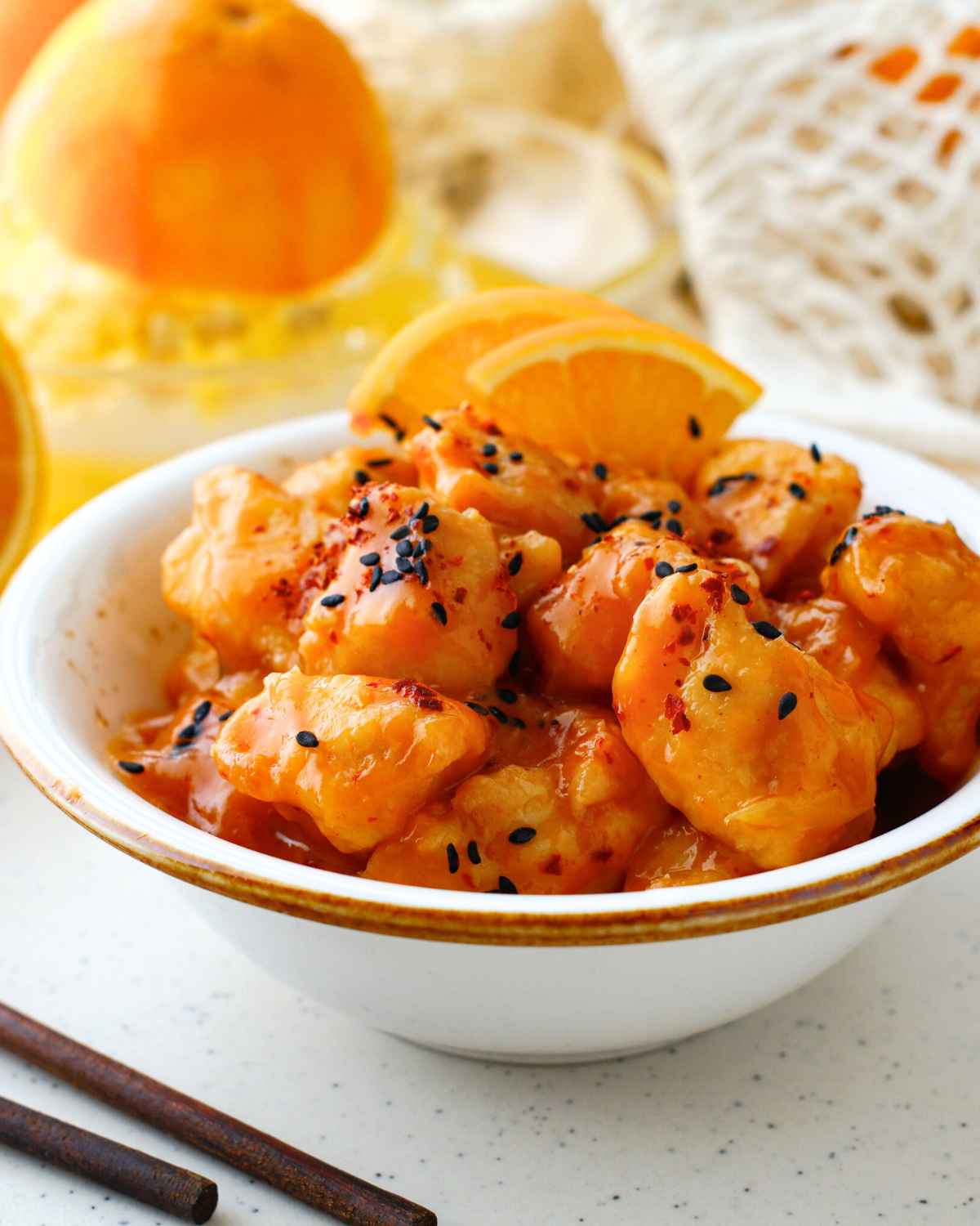 Spicy Orange Chicken in a bowl garnished with some lemon wedges