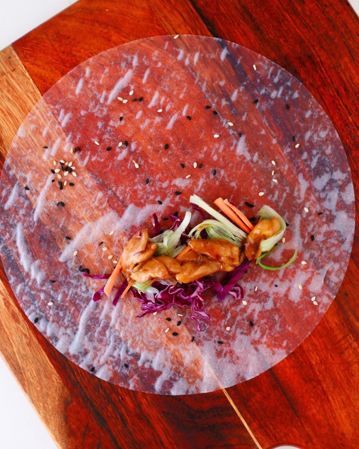 Rice paper topped with sesame seeds, vegetables and chicken