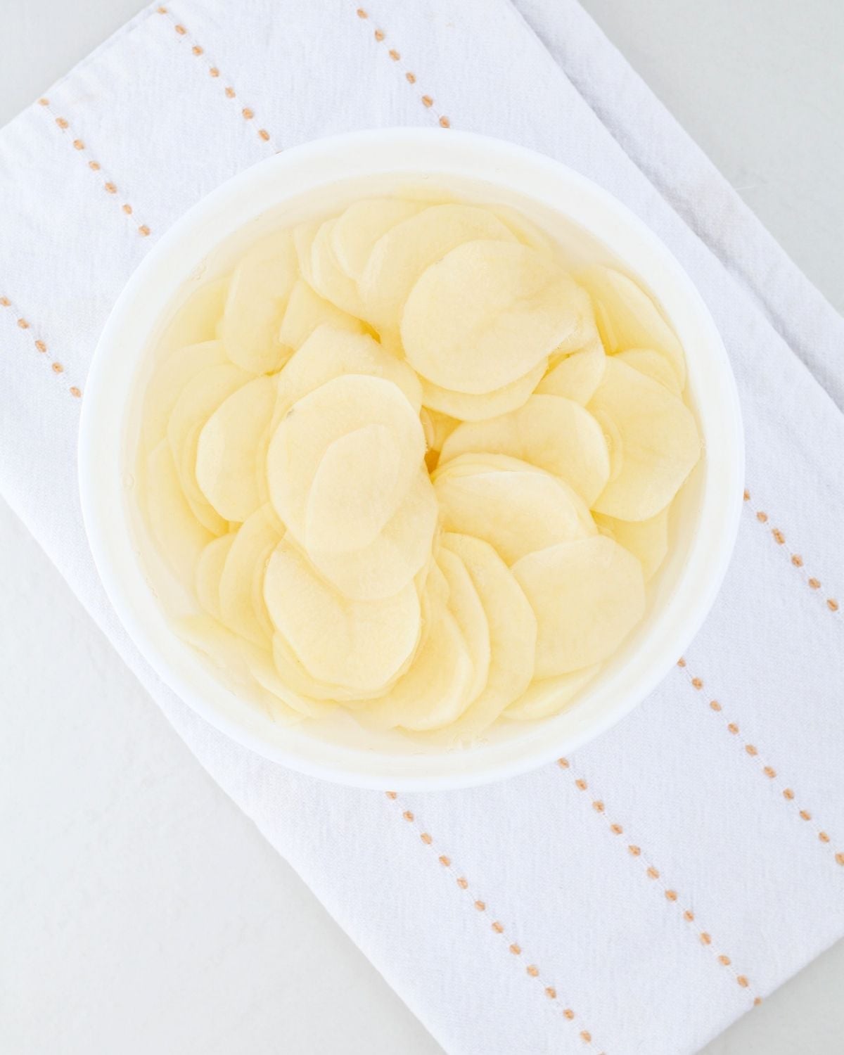 Thin potato slices soaking in cold water