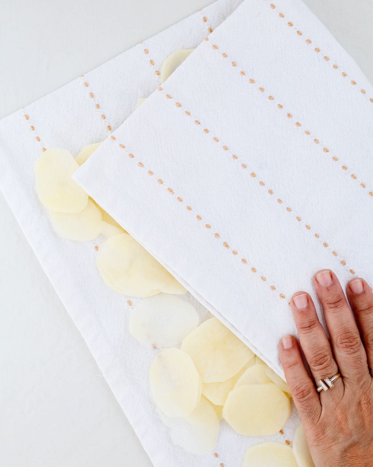Potato slices being dried with a kitchen towel