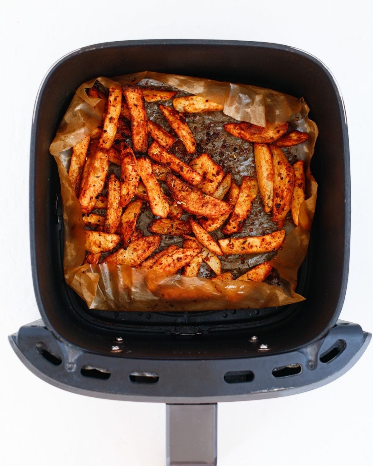 Golden seasoned fries in an air fryer basket