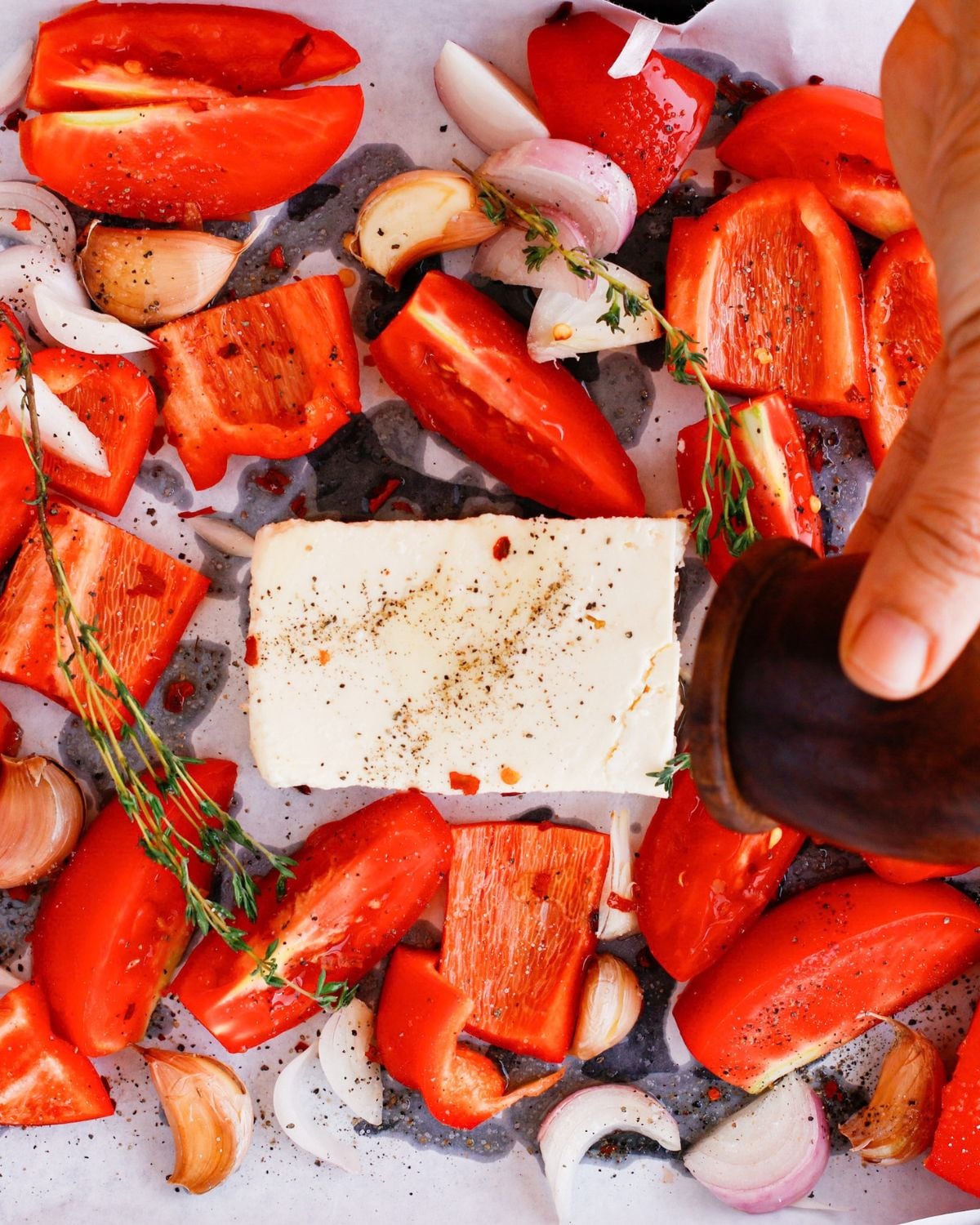 Vegetables, garlic, thyme and feta seasoned on a roasting tray